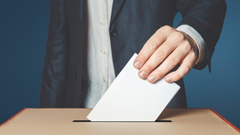 pessoa a introduzir boletim de voto numa urna
